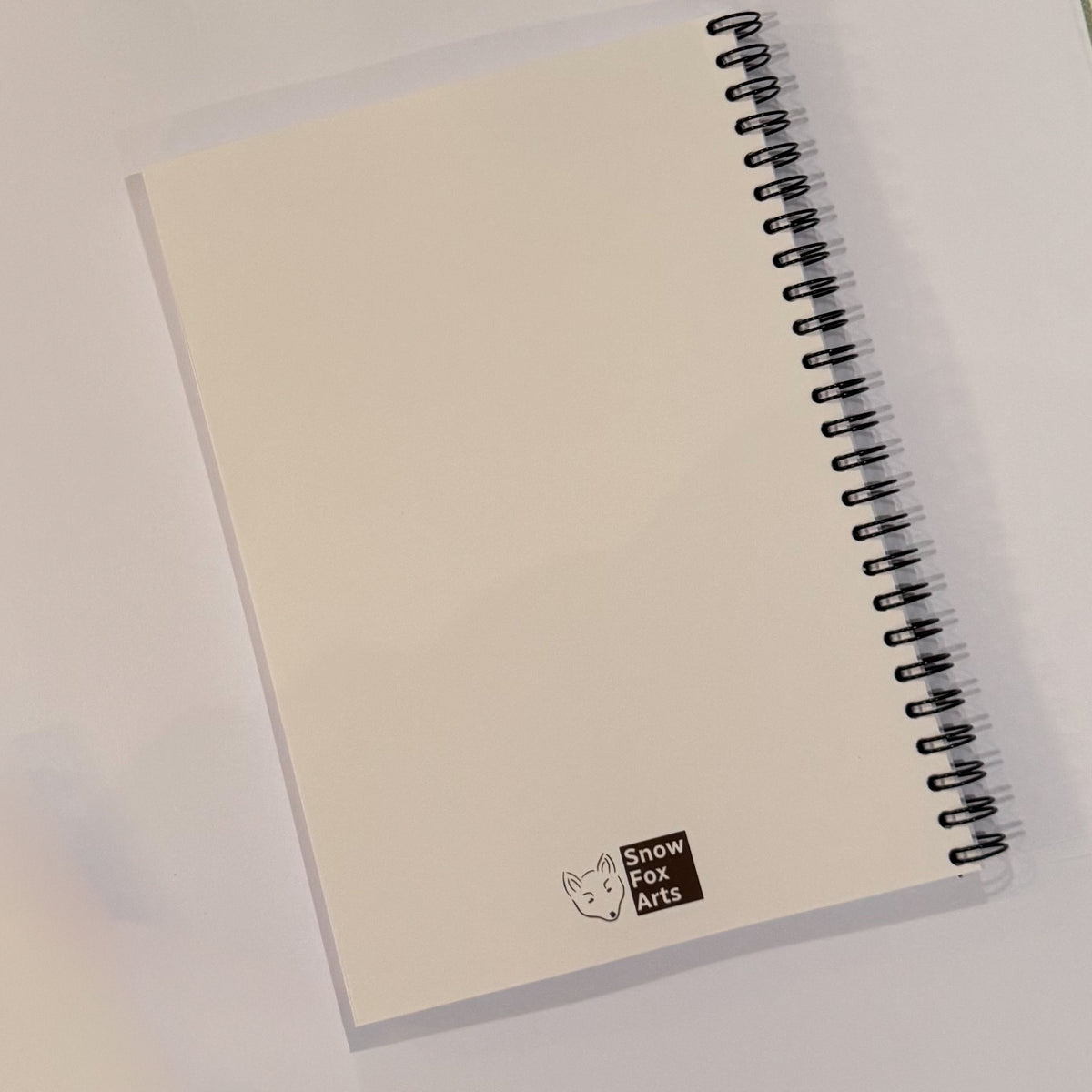 A blank cream-colored spiral notebook with a black wire binding and a small 'Snow Fox Arts' logo printed at the bottom, shown on a white background.