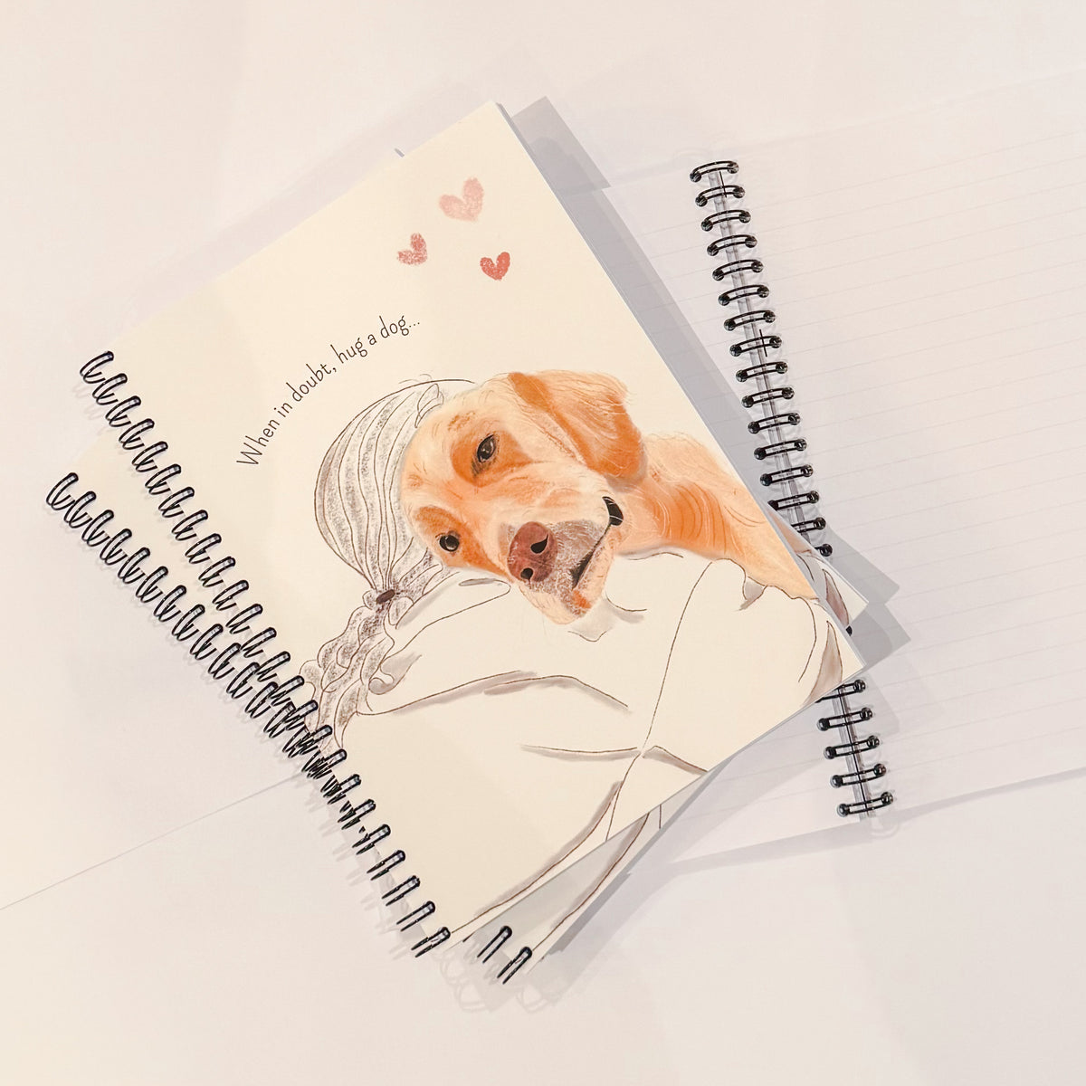 A spiral-bound notebook with an illustration of a golden retriever dog hugging a woman.
